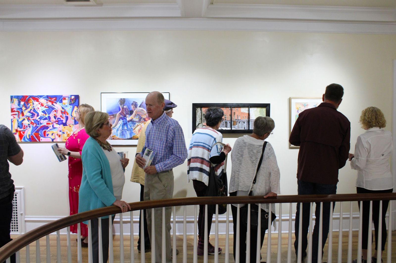 People look at art on the walls of a gallery.